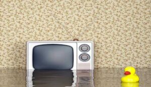 Room flooded with water reaching furniture and an old TV